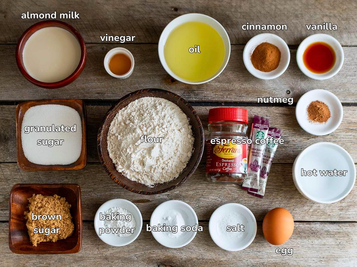 Ingredients to make a coffee snack cake laid out on a rustic wooden board all in little dishes. 