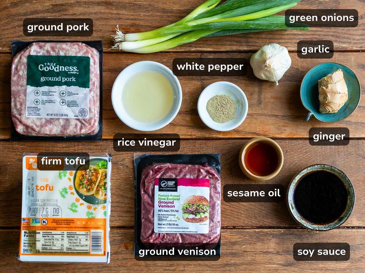 Ingredients to make deer meat meatballs laid out on a wooden table. 