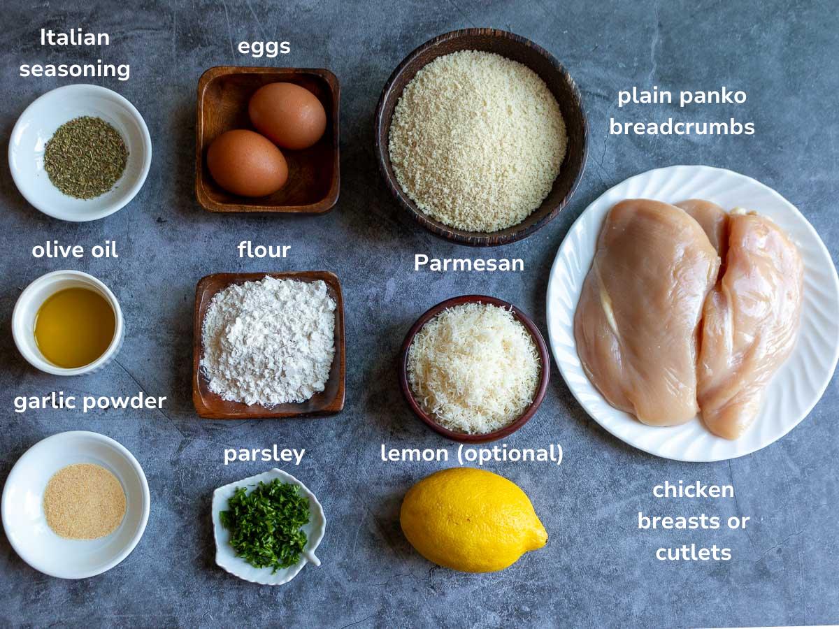 Ingredients to make Italian-style breaded cutlets on a gray table. 