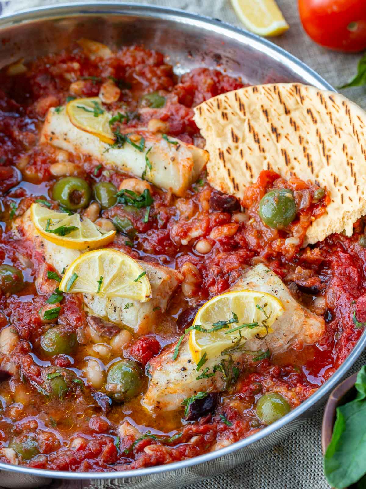 Dipping the flat breads into the briny olive and caper tomato sauce.