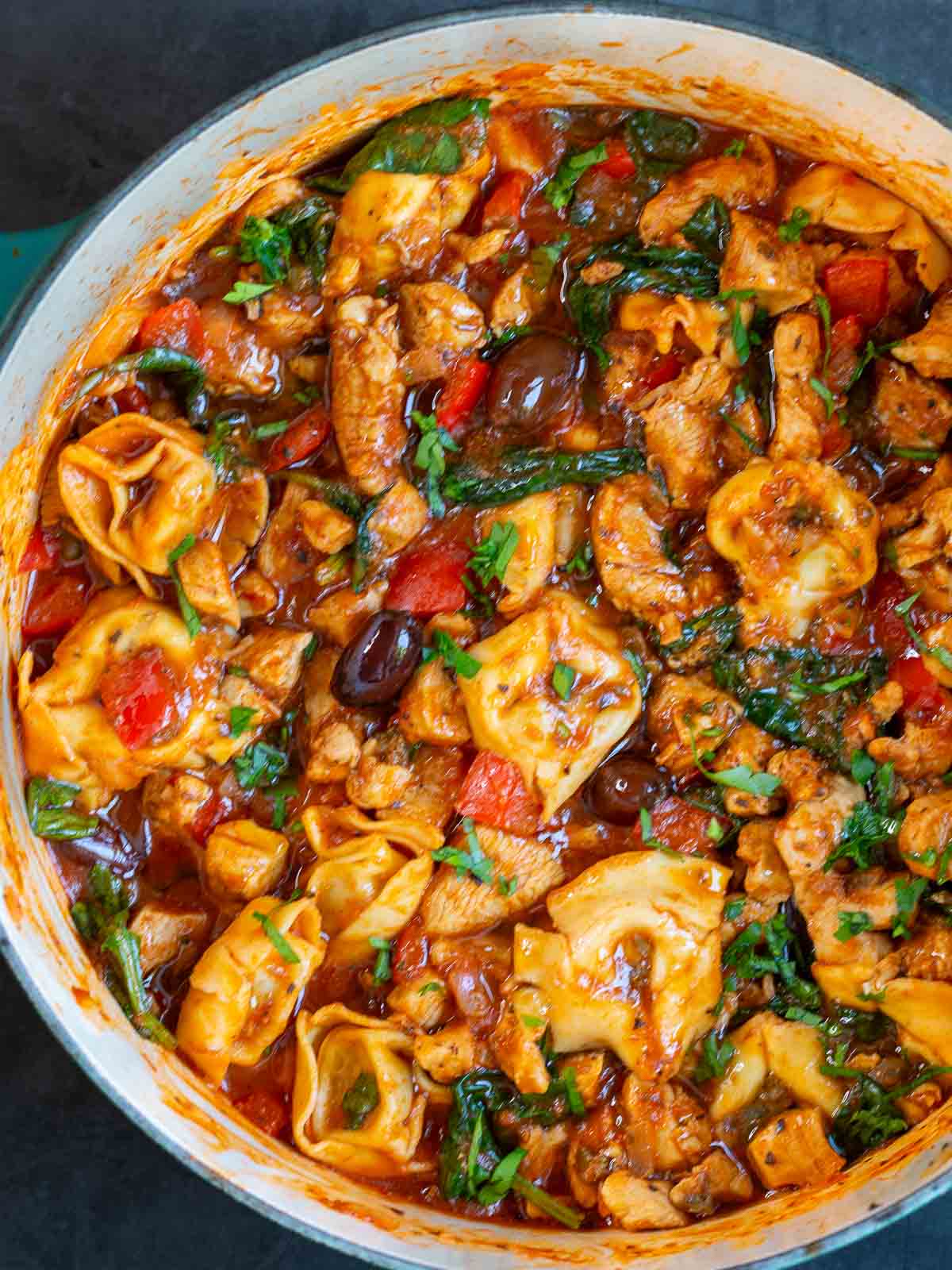 Cooked Italian cacciatore with tortellini in a Dutch oven pot.