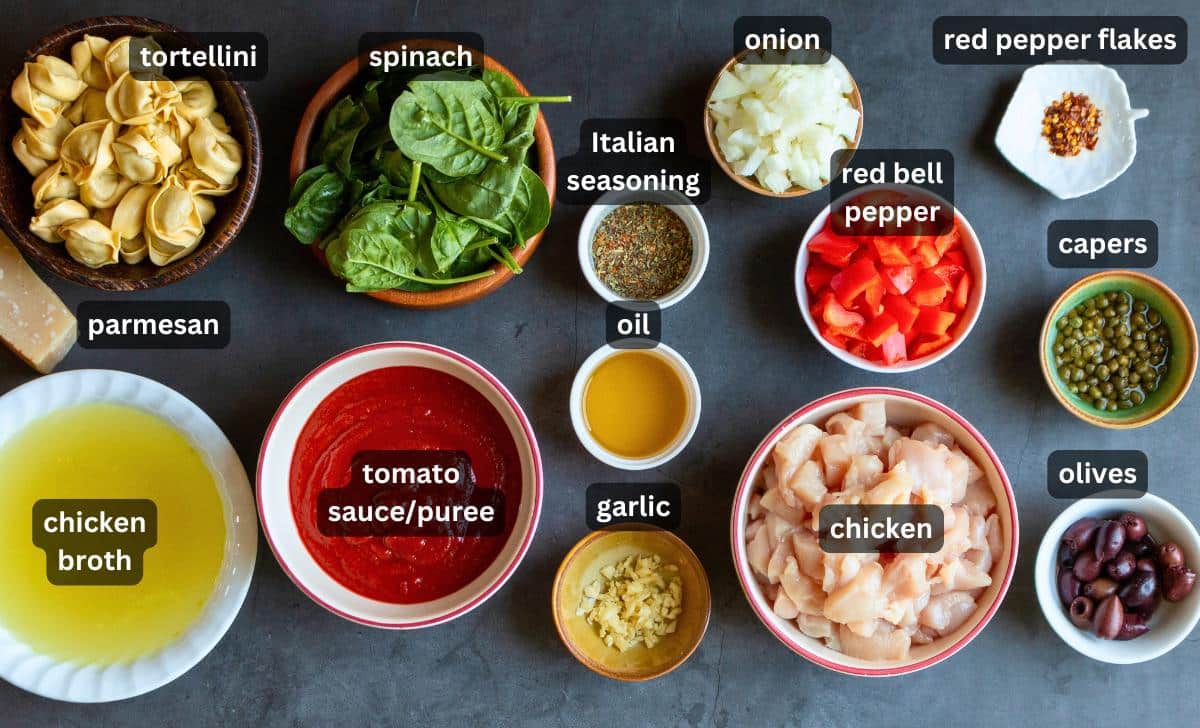 Ingredients to make chicken cacciatore with pasta laid out on a gray board. 