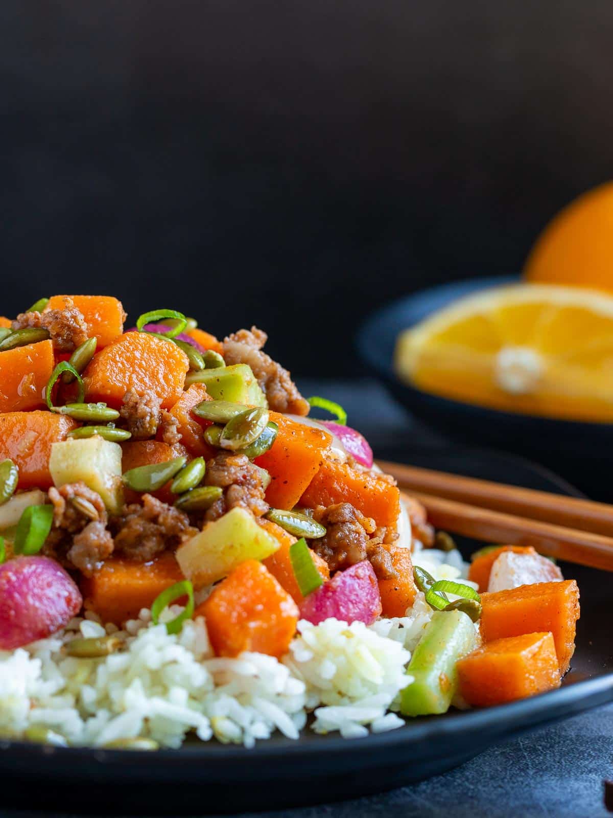 Close up shot of the Asian stir fry showing the toasted pepitas on top with the savory sausage and sweet potato.