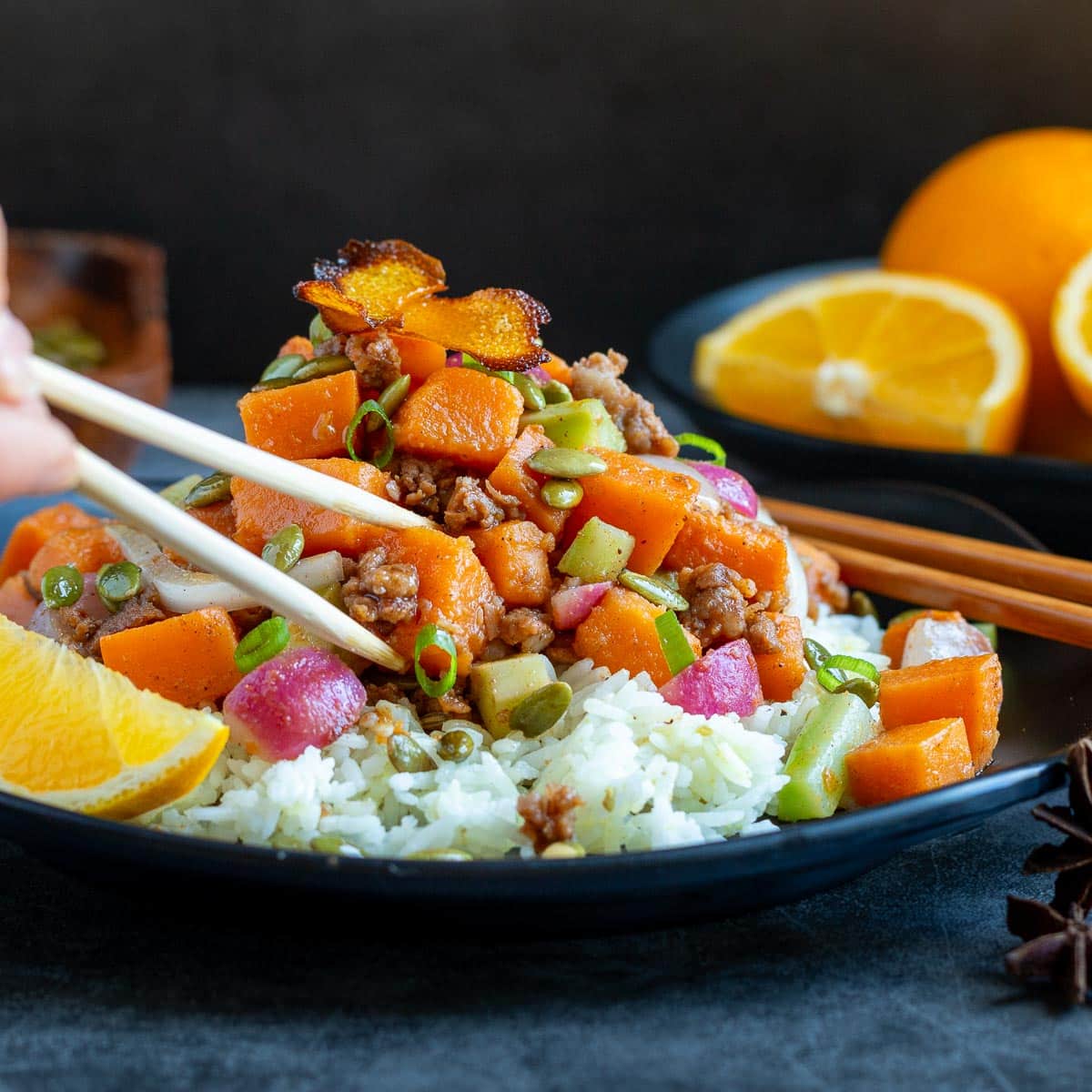 Using chop sticks to eat the Asian fusion stir fry dish with colorful vegetables. 