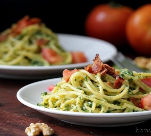 Spinach pesto pasta topped with bacon.