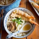 Tempura udon soup in a blue and white Japanese bowl with spoon.