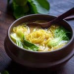 Golden Vermicelli Noodle Soup in a brown bowl with a wooden spoon.