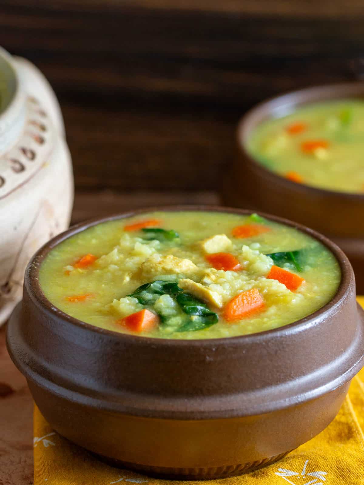 2 bowls of chicken and rice soup golden from the turmeric in brown Asian soup bowls. 