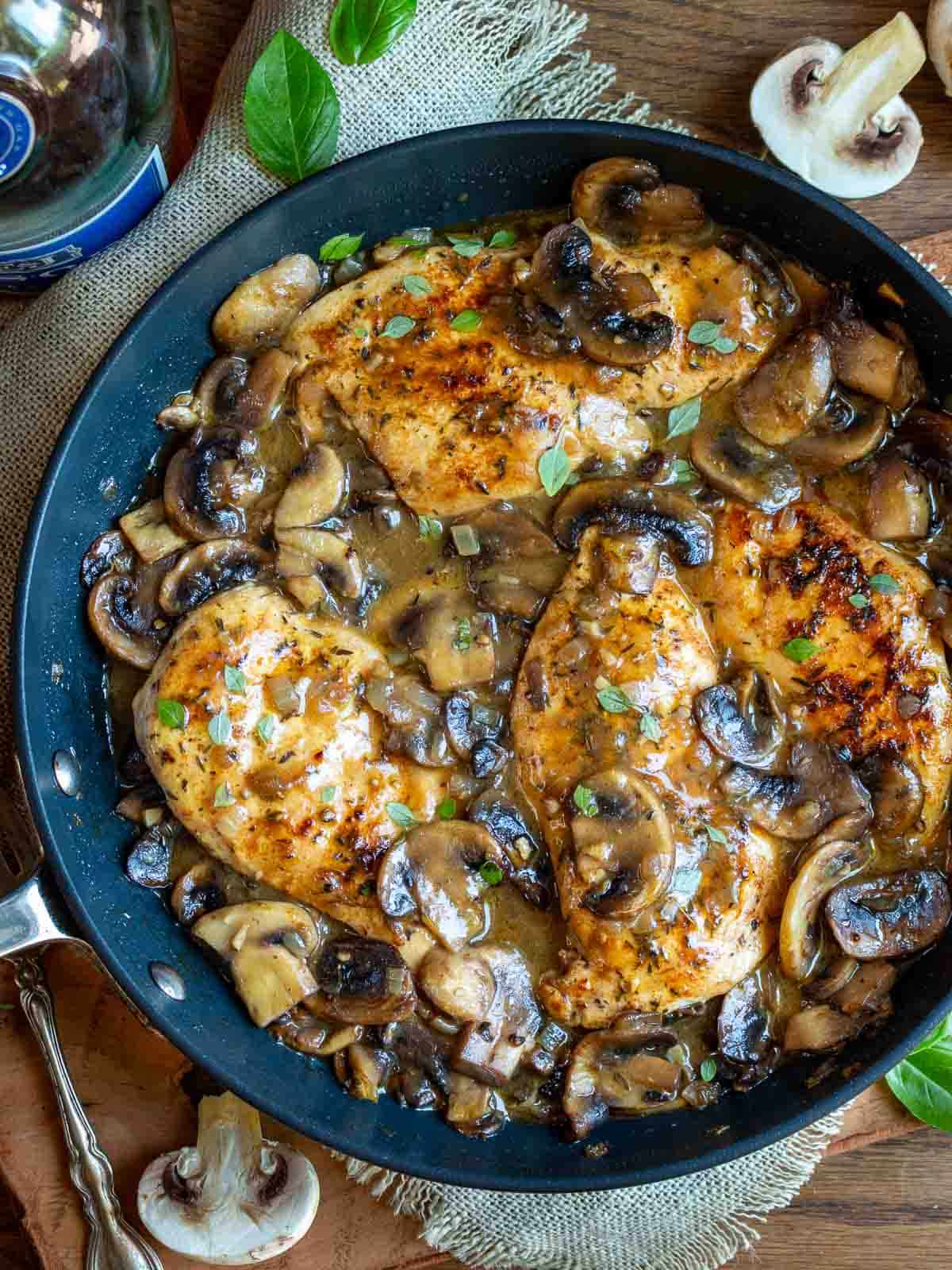 Recipe chicken and mushrooms in a black pan.