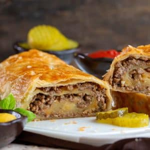 Baked cheese and ground beef puff pastry roll sliced into on a white cutting board.