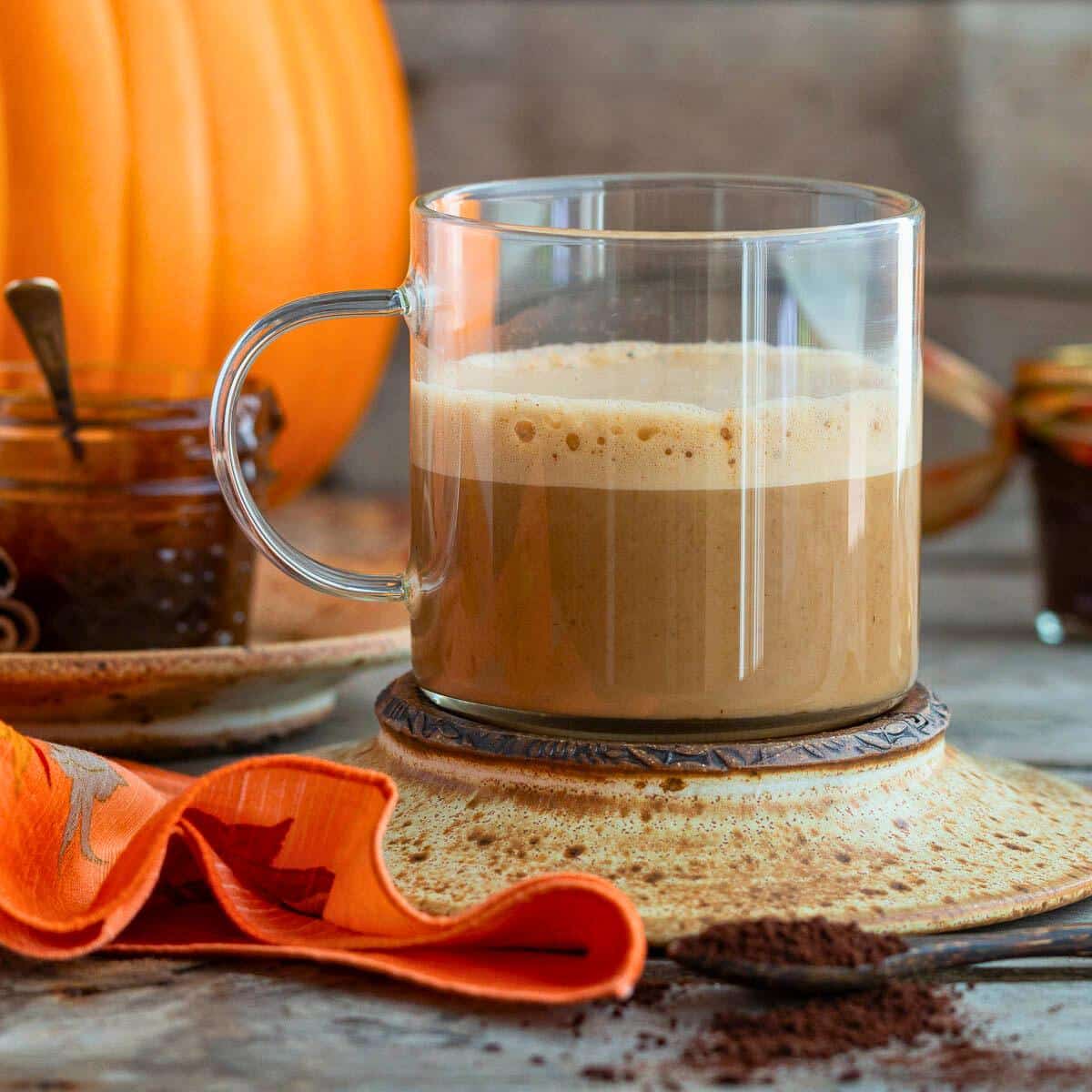 Pumpkin spice latte in a clear mug.