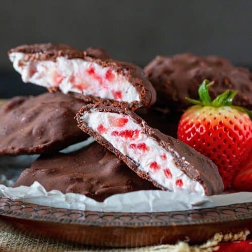 Chocolate frozen yogurt bites cut in halt showing the creamy Greek yogurt and strawberries coated in a thin magic shell.